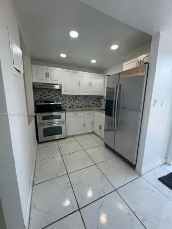 a kitchen with stainless steel appliances granite countertop a refrigerator and a stove top oven