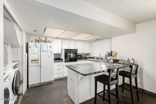 a kitchen with refrigerator and chairs