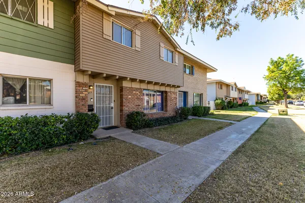 a view of a white house next to a yard with large trees