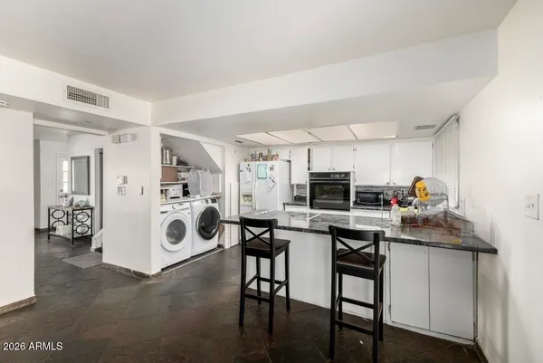 a kitchen with stainless steel appliances kitchen island granite countertop a stove and white cabinets
