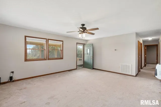an empty room with chandelier fan and windows