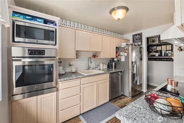 a kitchen with stainless steel appliances kitchen island granite countertop a refrigerator stove and sink