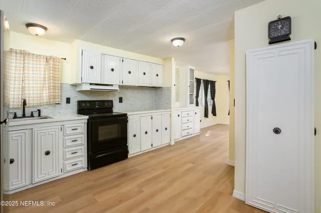 a kitchen with granite countertop a refrigerator stove and white cabinets