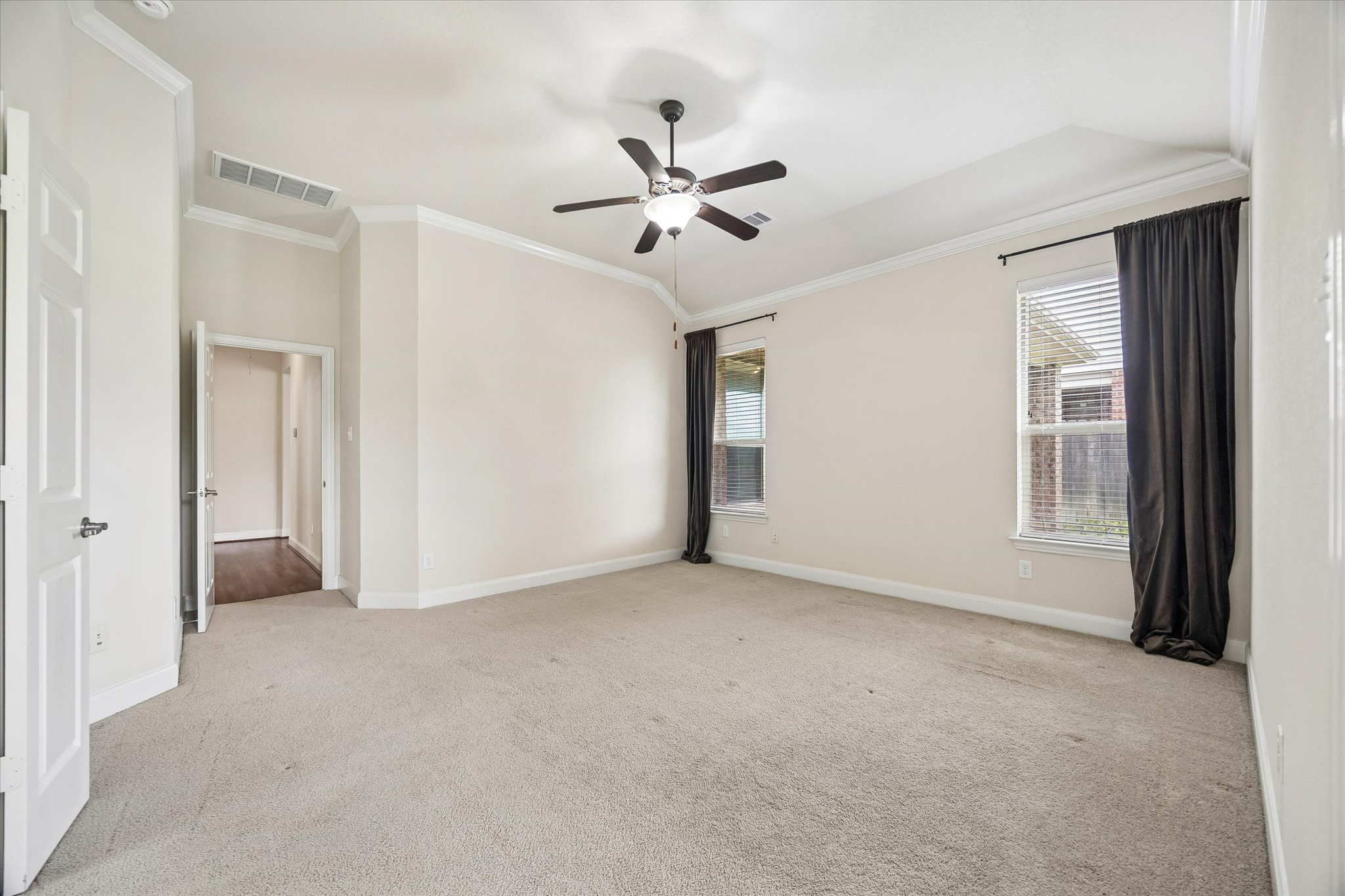 2214 Wembley Way Rosenberg, TX 77471 - Photo 23 of 35 Spacious room featuring tray ceiling, crown molding, light-colored carpeting, two windows with blinds, and a ceiling fan with integrated lighting