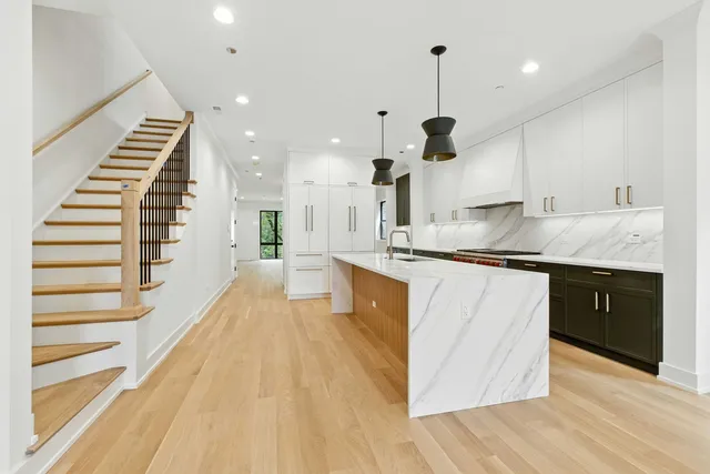 a large kitchen with stainless steel appliances kitchen island granite countertop a sink and a living room view