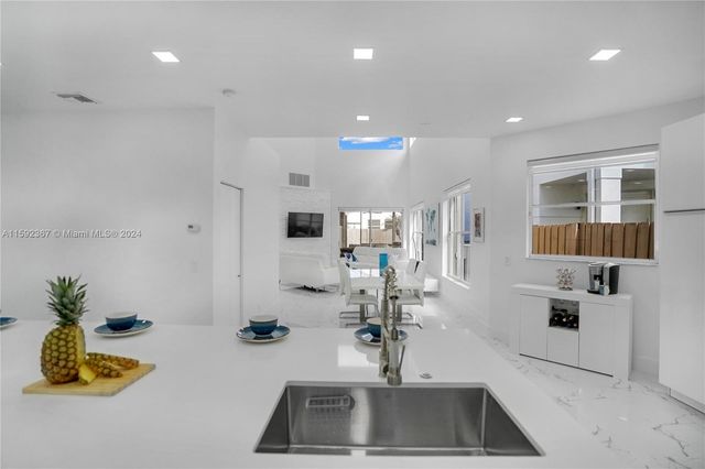 a living room with stainless steel appliances furniture a rug and a kitchen view