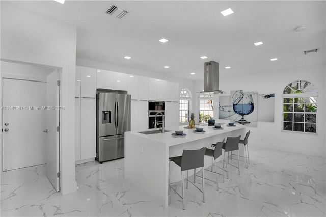 a very nice looking open dining room with kitchen island stainless steel appliances a table and chairs