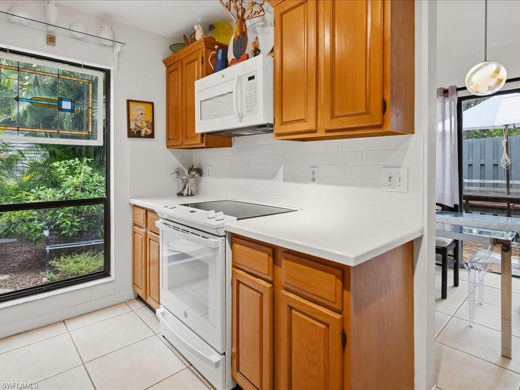 1337 Solana Road Naples, FL 34103 - Photo 9 of 23 Kitchen featuring wood cabinetry, white countertops, white subway tile backsplash, and a white electric range with a microwave above