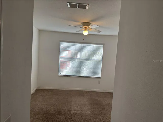 an empty room with a window and a fan