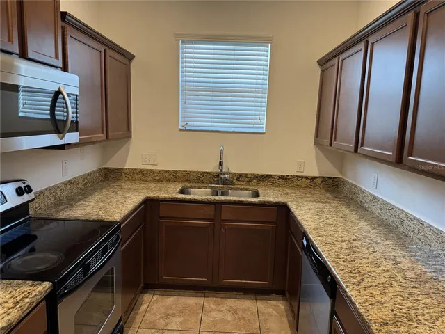 a kitchen with granite countertop a sink stove and cabinets