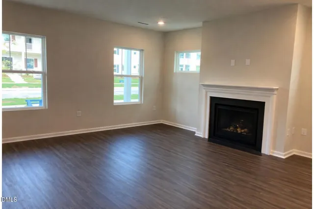 an empty room with wooden floor fireplace and windows