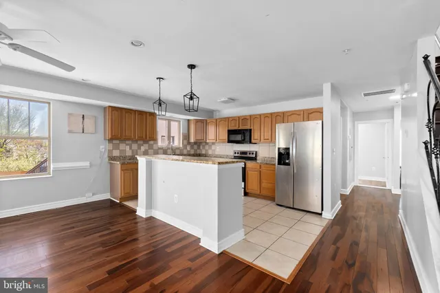 a kitchen with stainless steel appliances granite countertop a refrigerator a stove a sink dishwasher and white cabinets with wooden floor