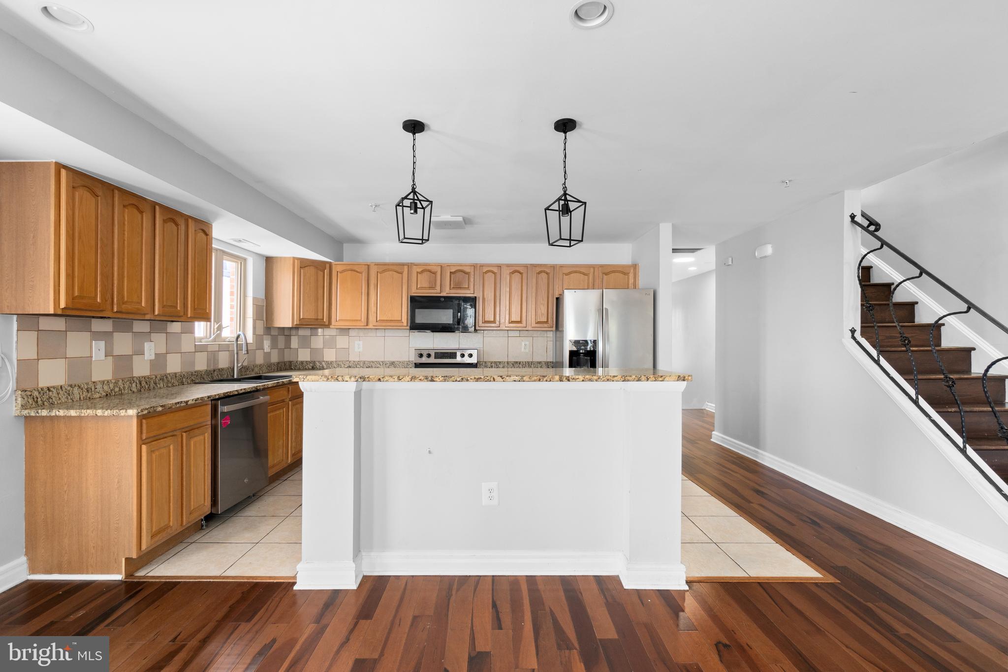 1829 Providence Street Northeast, Unit A Washington, DC 20002 - Photo 7 of 38 a large kitchen with stainless steel appliances granite countertop a refrigerator a stove a sink dishwasher and wooden cabinets with wooden floor