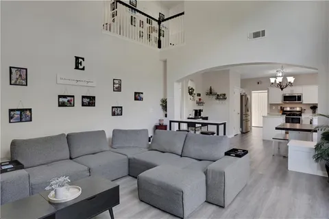 a living room with furniture kitchen view and a chandelier
