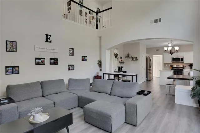 a living room with furniture kitchen view and a chandelier