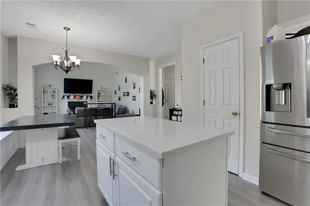 a kitchen that has a refrigerator a sink dishwasher a oven a dining table and chairs with wooden floor