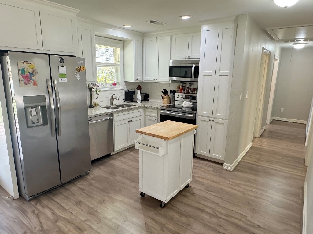 25827 Water Ridge Drive Huffman, TX 77336 - Photo 3 of 22 a kitchen with stainless steel appliances granite countertop a refrigerator a stove a sink and white cabinets with wooden floor