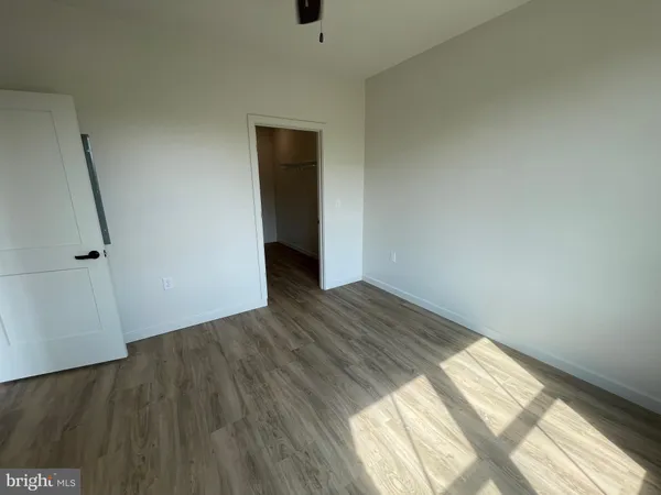 an empty room with wooden floor chandelier fan and windows