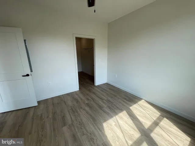 an empty room with wooden floor chandelier fan and windows
