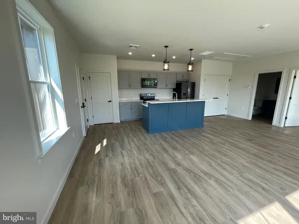 a view of a kitchen with kitchen island a sink wooden floor and a large window