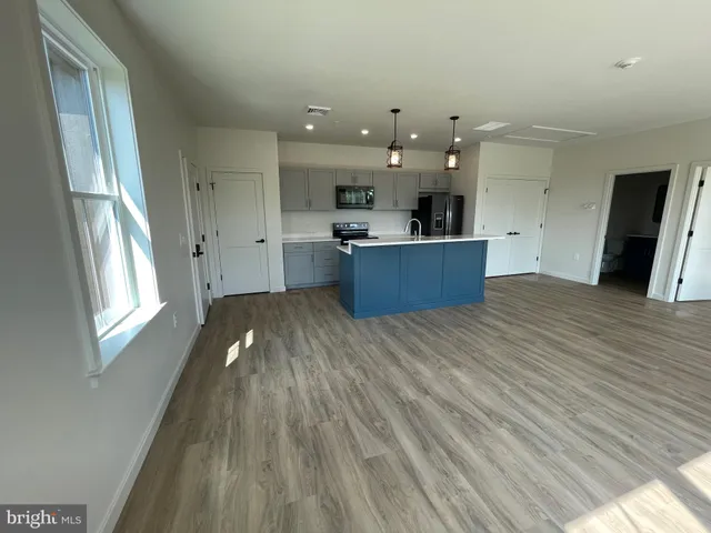 a view of a kitchen with kitchen island a sink wooden floor and a large window