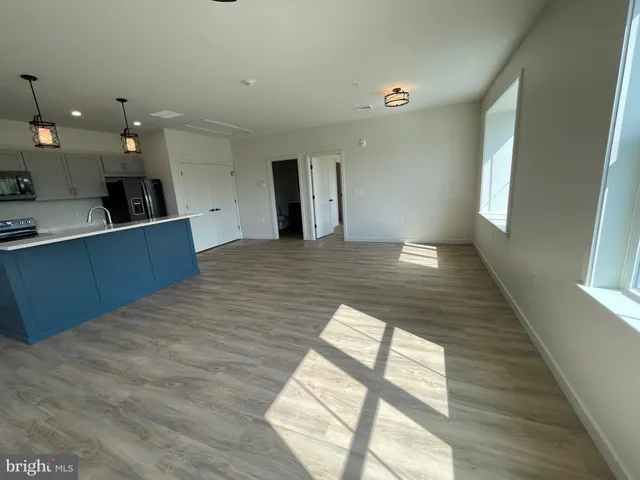 a large kitchen with kitchen island a sink wooden floor and a large window