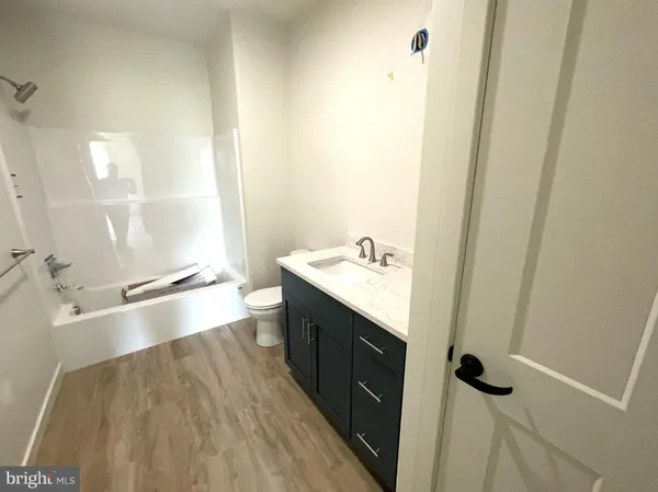 an empty room with wooden floor ceiling fan and windows
