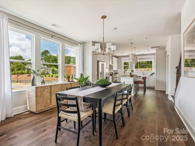 a view of a dining room and livingroom with furniture wooden floor a chandelier