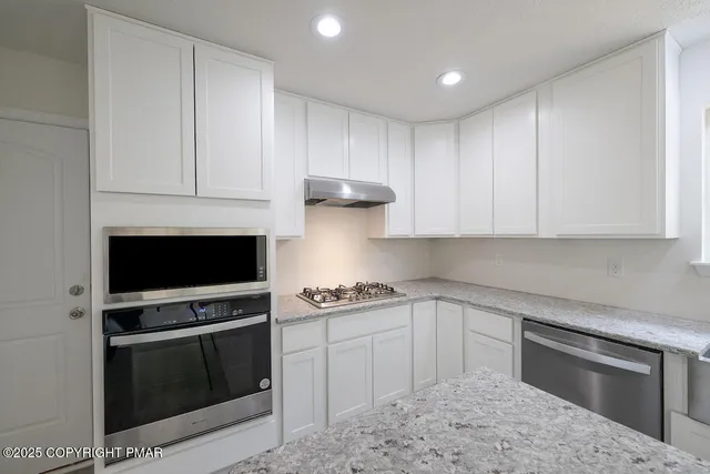 a kitchen with stainless steel appliances kitchen island granite countertop a stove a sink a dining table and chairs