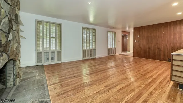 a view of an empty room with window and wooden floor