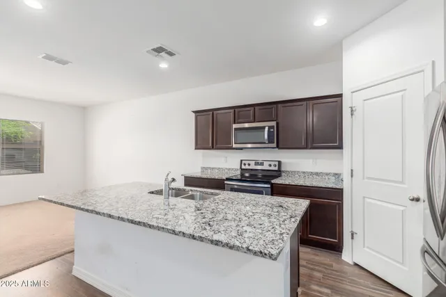 a kitchen with stainless steel appliances granite countertop a sink stove microwave and refrigerator