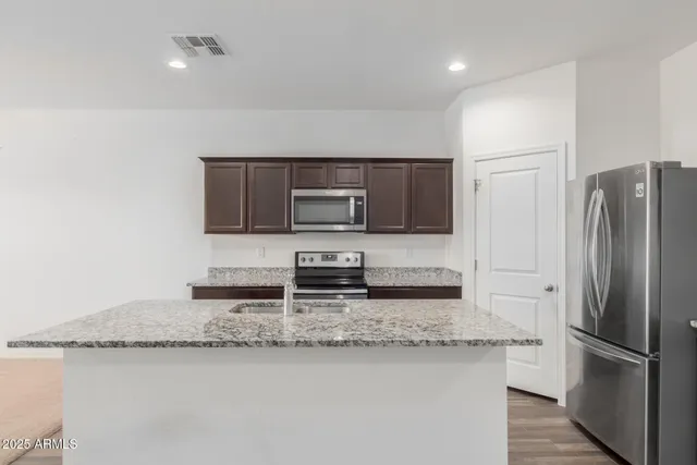 a kitchen with stainless steel appliances granite countertop a refrigerator a stove and a sink