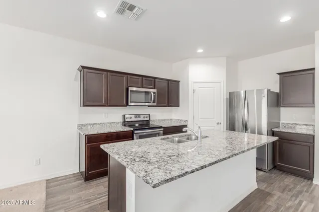 a kitchen with stainless steel appliances granite countertop a sink stove and refrigerator