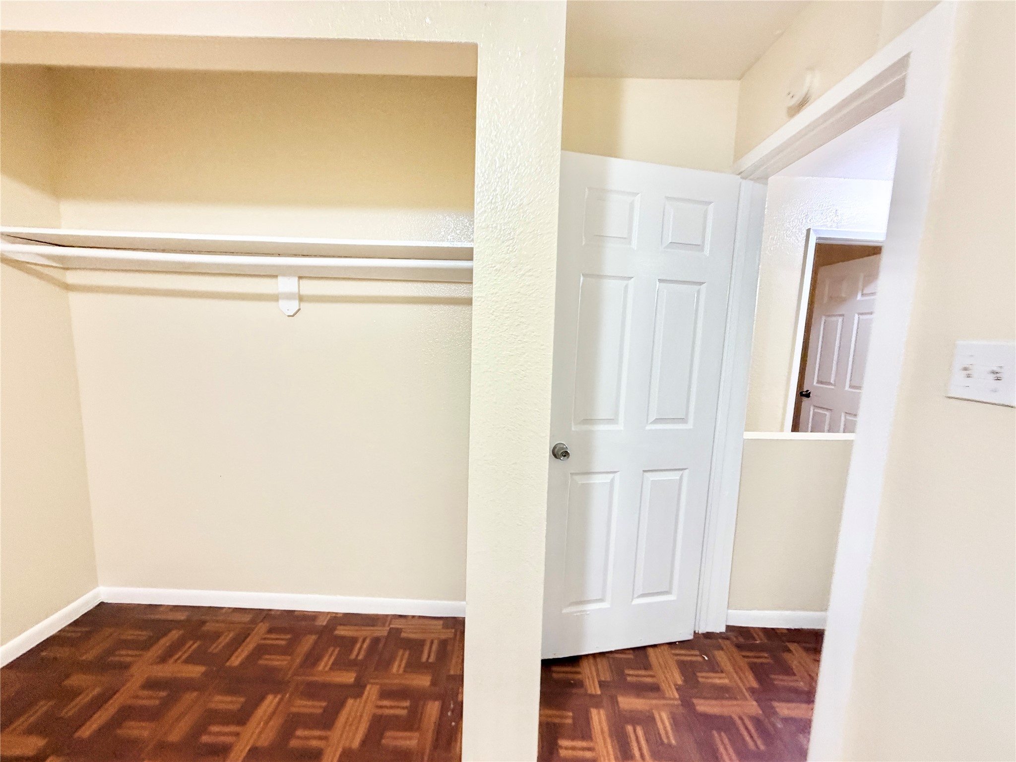 6257 Manor Road, Unit B Austin, TX 78723 - Photo 34 of 38 Bedroom featuring wood-finish parquet flooring, light neutral-toned walls, a built-in closet with shelving and hanging rod, and a white paneled door