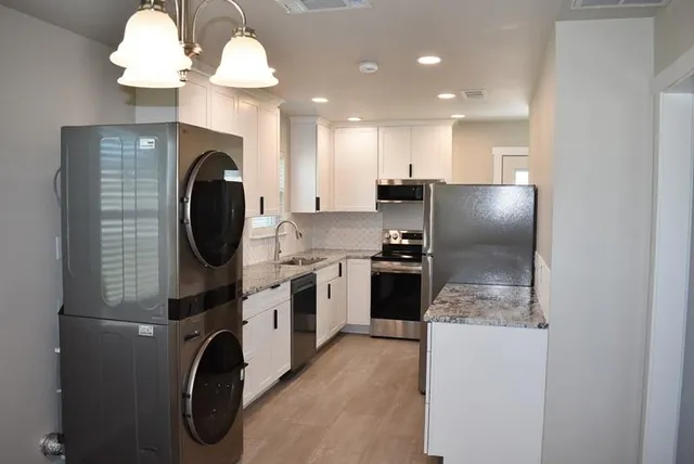 a kitchen with stainless steel appliances granite countertop a washer and dryer