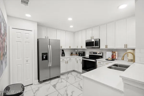 a kitchen with a refrigerator sink and white cabinets