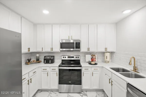 a kitchen with appliances a sink and cabinets