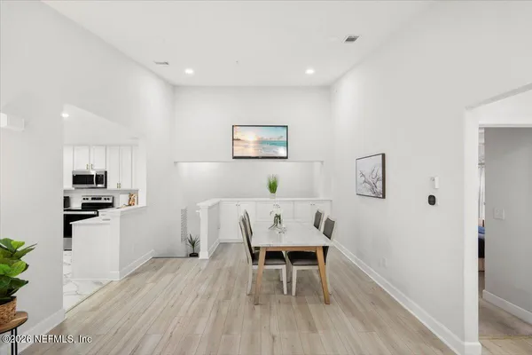 a living room with furniture a dining table wooden floor and a refrigerator