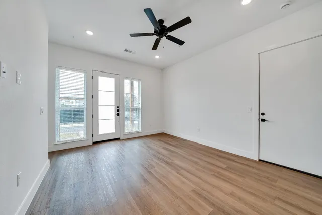 a view of an empty room with a window and wooden floor