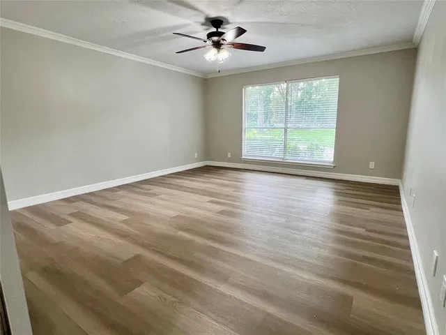 an empty room with wooden floor fan and windows