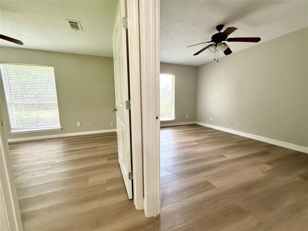 14221 Horseshoe Bend Conroe, TX 77384 - Photo 15 of 21 an empty room with wooden floor fan and windows
