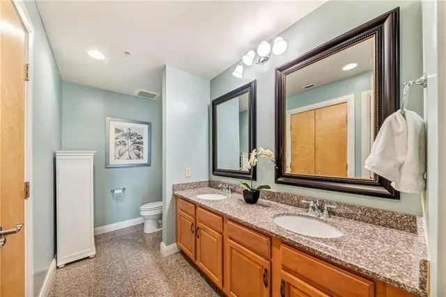 a bathroom with a granite countertop double vanity sink and a mirror