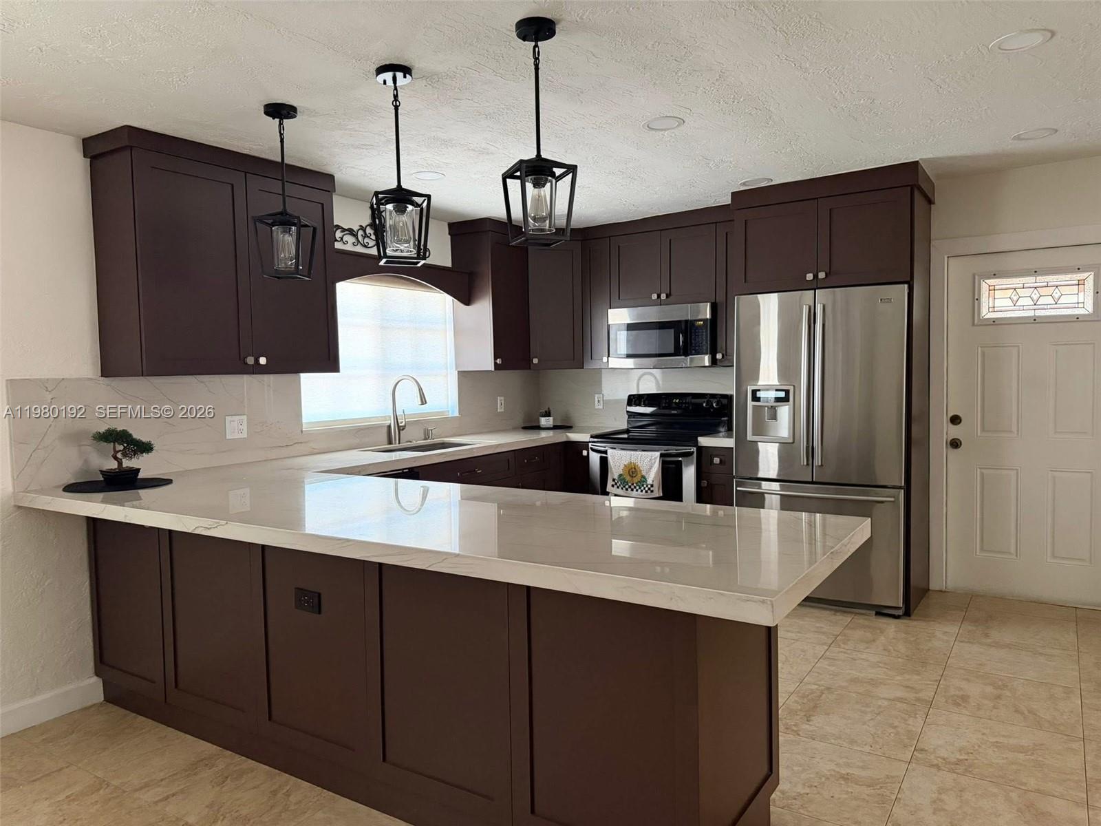 4161 Southwest 97th Place Miami, FL 33165 - Photo 3 of 19 a kitchen with kitchen island a counter space a sink and refrigerator