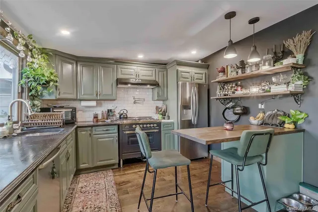 a kitchen with stainless steel appliances granite countertop a sink a stove a refrigerator cabinets and chairs