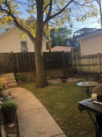 a view of backyard with wooden fence and a large tree