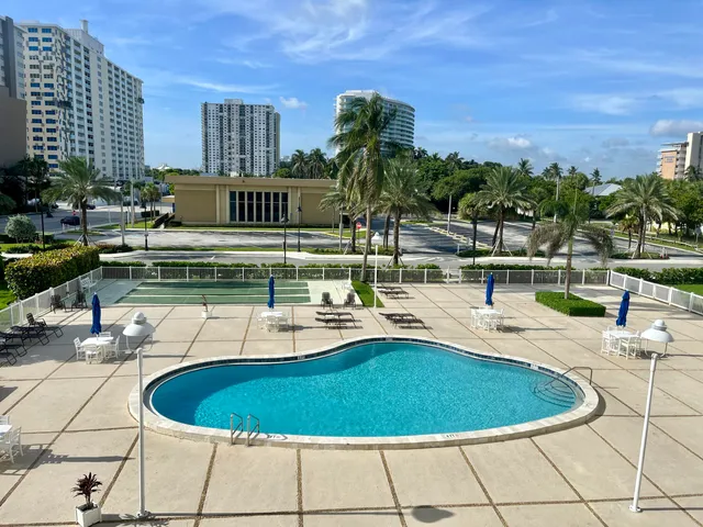 a blue swimming pool with outdoor seating and yard in the back
