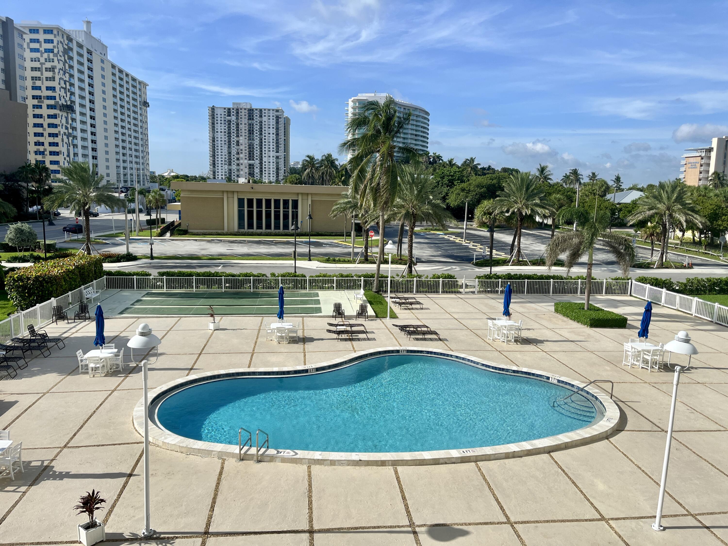 201 North Ocean Boulevard, Unit 302 Pompano Beach, FL 33062 - Photo 21 of 39 a blue swimming pool with outdoor seating and yard in the back