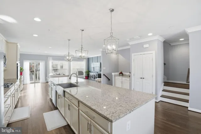 a kitchen with stainless steel appliances granite countertop a sink a counter top space and living room view