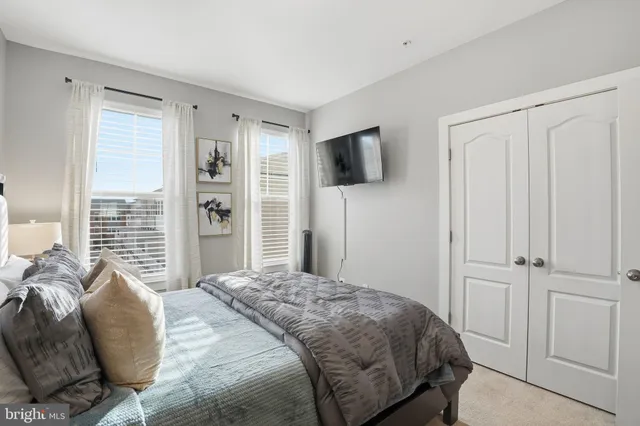 a bedroom with a bed a flat screen tv and a window