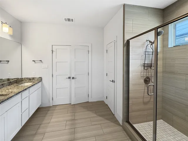 a bathroom with a granite countertop sink a mirror and a shower